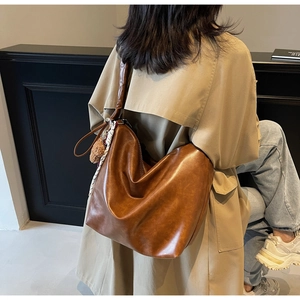Brown faux leather tote bag with wide strap and decorative plush bear charm detail