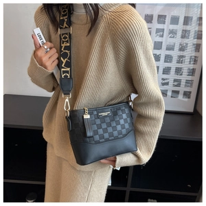 Detail of black crossbody bucket bag featuring checkered texture and wide embroidered strap