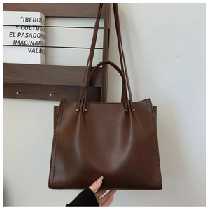 Detail of dark brown faux leather tote bag with silver rivets and dual shoulder straps
