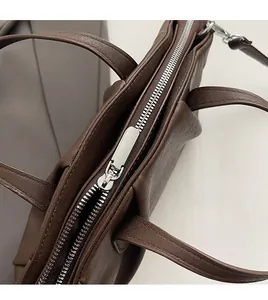 Detail of smooth silver metal zipper on premium brown faux leather handbag with lychee grain