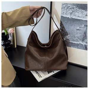 Detail of dark brown vintage faux leather tote bag with stylish pleated texture and stitching