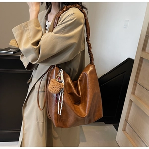 Detail of vintage brown PU leather hobo bag with scrunchie strap and plush bear charm