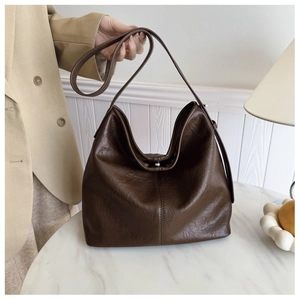 Close-up of deep brown oil-wax leather tote bag with vintage texture and metal clasp