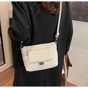 Close-up of off-white corduroy shoulder bag with elegant gold metal twist lock