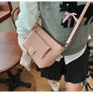 Close-up of pink pleated crossbody bag featuring a golden metallic twist lock and flap