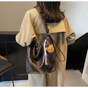 Detail of coffee brown slouchy tote bag with pleated strap and cute bear charm