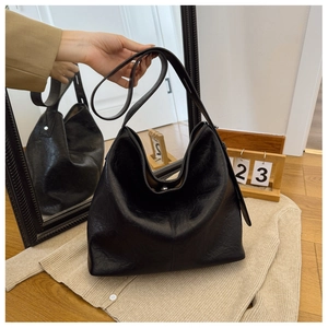 Detail of black pebbled leather tote bag shown against a wooden mirror reflection