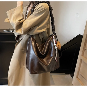 Detail of dark brown leather hobo bag with scrunchie strap and plush bear charm decoration