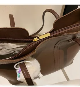 Detail view of smooth golden zipper closure and inner lining on a brown leather tote bag