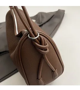 Detail of dark brown leather tote with vertical stripe texture and silver metal rings