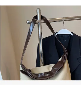 Close-up of contrast canvas tote bag with brown leather trim and silver metal twist lock