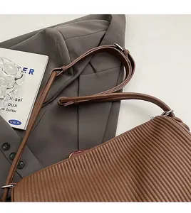 Detail of vintage brown shoulder bag showing vertical pleated texture and silver buckle
