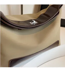 Detailed close-up of khaki canvas and brown leather stitching with silver metal twist lock