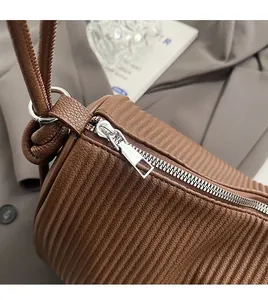 Detailed shot of smooth silver metal zipper on brown pleated striped tote bag