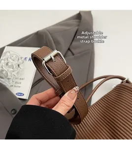 Macro view of adjustable silver buckle on a brown lychee pattern leather tote bag