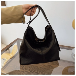 Detail of a black leather hobo bag with wide strap and decorative stitching accents