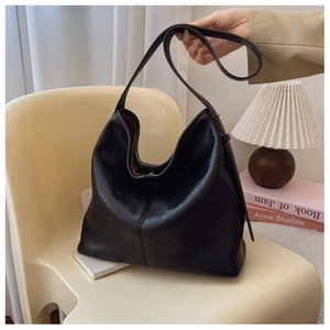 Detail of black Hobo bag with textured pleated synthetic leather on an artistic chair