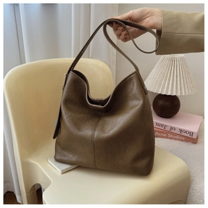 Detail of deep brown textured leather hobo bag on a minimalist modern chair