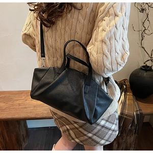 Detail of black pleated cloud bag with soft matte finish and elegant round handle