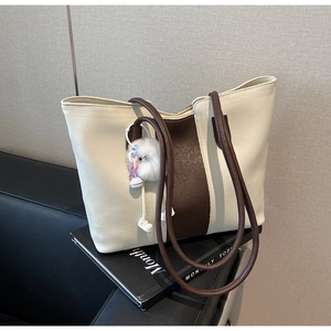 Detail of the large capacity tote bag with brown contrast stitching and plush charm