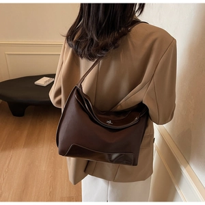 Detail view of a vintage dark brown shoulder bag with mixed leather texture and silver buckle
