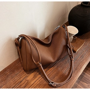 Detail of caramel brown pleated leather pillow bag showing cylindrical shape and straps