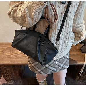 Close-up of black pleated PU leather handbag showing natural texture and crossbody strap
