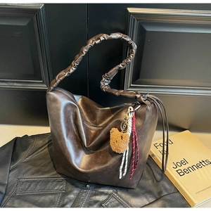 Detail of vintage brown oil wax leather hobo bag with teddy charm and pleated handle