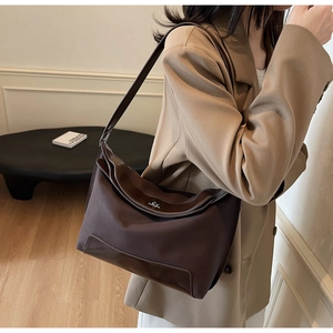 Detail of a dark brown nylon and leather bag with a stylish silver twist lock buckle