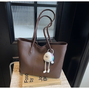 Close-up of brown faux leather tote bag texture with cute plush doll charm