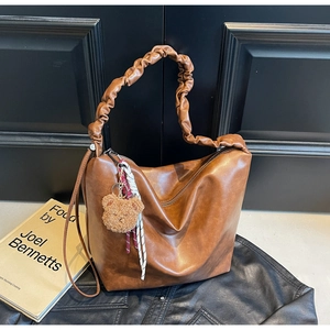 Detailed view of brown PU leather bag with pleated handle and plush bear charm