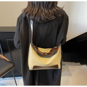 Fashionable hobo shoulder bag in canvas and leather on a model wearing a black coat