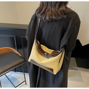 Detail view of vintage canvas and brown leather crossbody bag styled with a black blazer