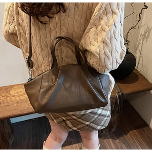 Close-up of dark brown wrinkled PU leather handbag with cylindrical handles and strap