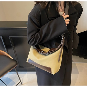 Detail of hobo bag with beige canvas, dark brown leather trim, and silver twist lock