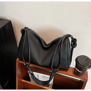 Detail of black pleated texture shoulder bag with knotted strap and silver hardware accents