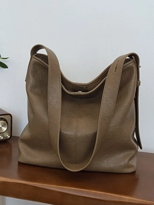 Retro brown large capacity PU leather tote bag with wide strap on a wooden desk