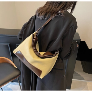 Detail of a large two-tone canvas and brown leather shoulder bag shown on a model