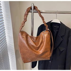 Detail of dark brown matte PU leather tote with ruched shoulder strap and zipper closure