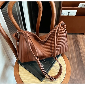 Detail of the brown pleated leather texture and metallic zipper of the shoulder bag