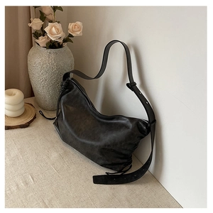 Detail of black leather hobo bag with vintage texture and adjustable strap in a home setting