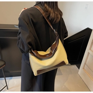 Detailed side view of the khaki canvas hobo bag with brown leather trim and metal lock