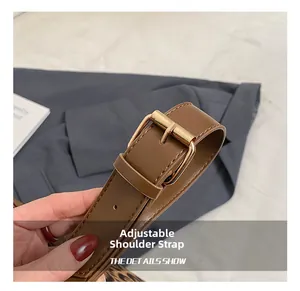 Detail of adjustable brown leather shoulder strap with a golden metal buckle and fine stitching