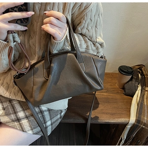 Detail of dark brown pleated PU leather bag with adjustable straps and soft texture