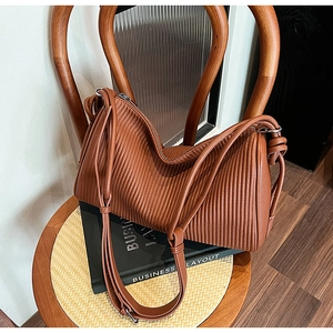Detailed view of the brown pleated texture and silver metallic buckle of the stylish handbag