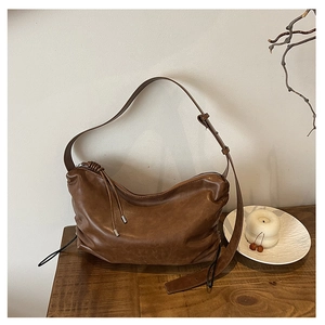 Detail of dark brown vintage pleated shoulder bag showing supple leather texture and metal buckle