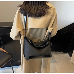 Detail of a large black nylon and leather crossbody bag shown on a model in a minimalist room