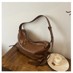 Detail view of brown PU leather hobo bag with drawstring and knotted strap design