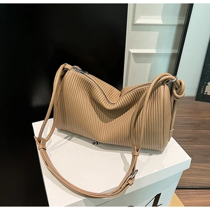 Detail of camel shoulder bag featuring vertical pleated texture and silver zipper hardware