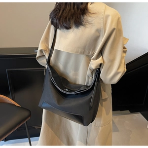 Detailed view of black matte nylon tote bag worn by model in a stylish urban setting